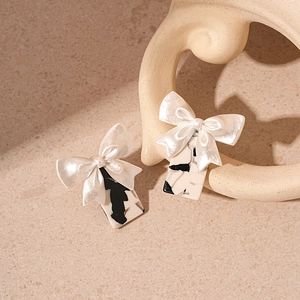 Detail of vintage white resin bow earrings with black marble pattern square pendants