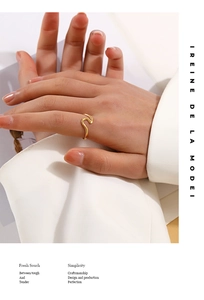 Close-up of minimalist wave-shaped gold open ring on model hand with elegant lighting