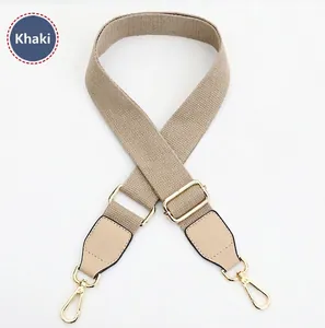 Detail view of khaki adjustable canvas bag strap with golden metal swivel hooks