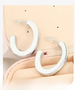 Polished silver C-shaped earrings with silicone plugs in a pink velvet jewelry box