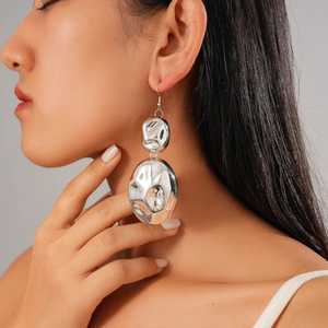 Close-up of model wearing silver irregular textured double oval drop earrings in metal