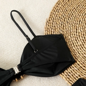 Macro detail of black bikini with silver buckle and gold floral rhinestone embellishment