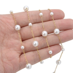 Macro detail of mixed size white pearls on a gold-tone 18K metal link chain jewelry part