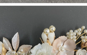 Close-up of bridal hair comb featuring white ceramic flowers, pearls and golden leaves
