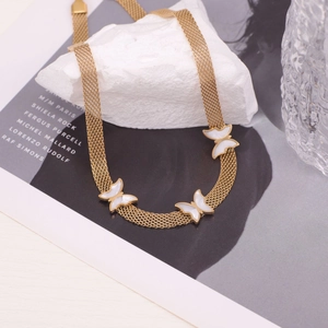 Golden woven chain necklace with white butterfly charms on a fashion magazine background