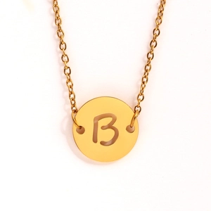 Détail d'un collier en acier doré avec un pendentif rond ajouré et la lettre B