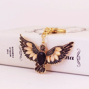 Vintage golden eagle keychain with black and yellow crystals on a decorative book