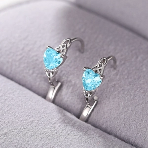 Macro detail of heart-shaped blue gemstone earrings with Celtic knot silver design