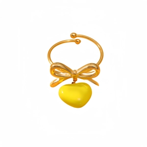 Golden stainless steel bow ring with yellow heart pendant on a clean white background