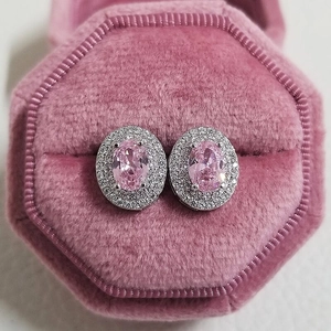 Close-up of pink oval zircon stud earrings with double halo in a velvet jewelry box