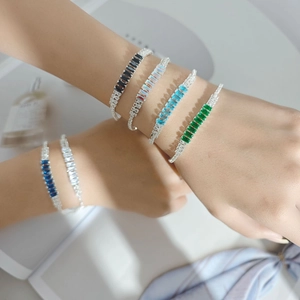 Macro detail of layered colorful zircon bracelets with rectangle cut stones on female wrist