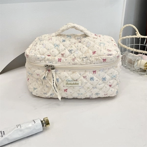 Close-up of quilted makeup bag featuring cute bunny and bow prints with a sturdy top handle
