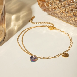 Detail view of a double-layered 16k gold butterfly anklet with crystal heart charm