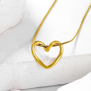 Macro shot of gold heart pendant with twist detail on a polished snake chain necklace
