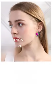 Close-up of vibrant heart-shaped crystal earrings with colorful rhinestones on a model