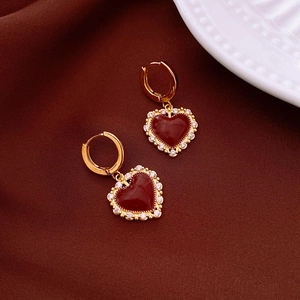 Detailed close-up of gold plated heart earrings with red enamel and pavé zircon stones