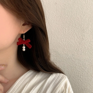Red velvet bow earrings with white faux pearls on model for a vintage aesthetic look