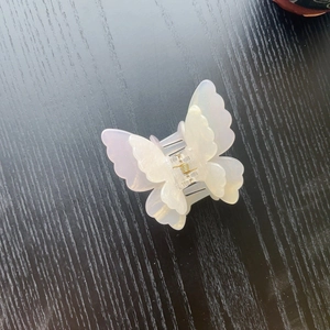 Detail of pearlescent white butterfly hair claw clip with golden metal spring