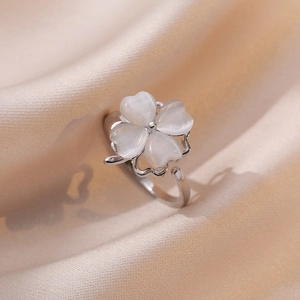 Elegant rotating four-leaf clover ring with white cat eye stone on silk fabric