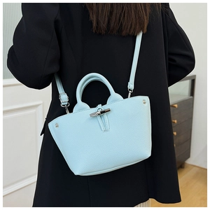 Detail of light blue lychee pattern leather handbag with silver bamboo clasp and strap