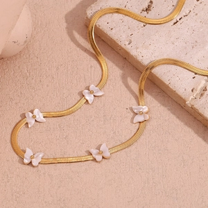 Macro shot of 18K gold-plated blade chain with white butterfly pendants on stone