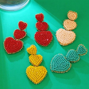 Detail showing three-tier beaded heart drop earrings in red, white, yellow, and blue