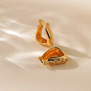 Detailed view of gold plated earrings featuring star patterns and clear zircon stones