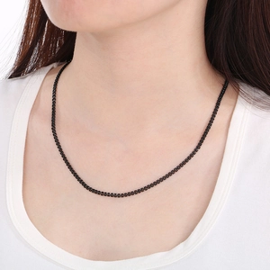 Detailopname van een zwarte visgraat ketting van roestvrij staal op de hals van een model