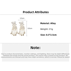 Detail view of gold butterfly tassel earrings with alloy pendant and bell drop design