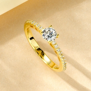 Top view of 14k gold-plated moissanite ring with a large center stone on sand background