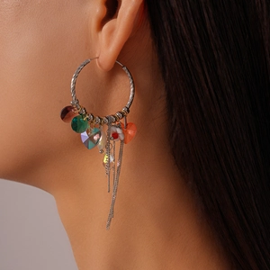 Close-up of silver hoop earrings with colorful heart charms and delicate chain tassels