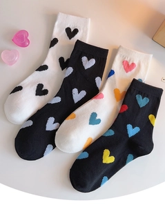 Detailed view of white and black cotton socks with colorful heart patterns laid on table
