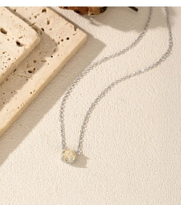 Macro detail of S925 silver necklace with yellow rose-cut zircon on beige stone texture