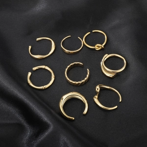 8-piece set of minimalist gold stainless steel rings on a black silk satin fabric background