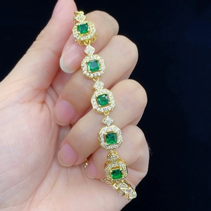 Elegantes Goldarmband mit quadratischen grünen Edelsteinen und weißen Diamanten auf Schwarz