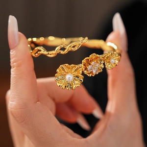 Detail of vintage flower bracelet with gold plating, pearls, and zircons on a model's wrist