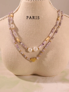 Detail of double-layer beaded necklace with purple stones, white pearls and gold heart charm