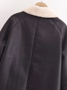 Detail of faux leather texture and white faux shearling collar on back of black jacket