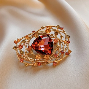Close-up of vintage flower brooch with large red gemstone and multi-color rhinestones