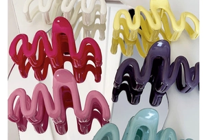 Close-up of colorful wave-shaped large hair claw clips displayed on a mirror surface