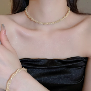 Close-up of gold woven texture necklace and bracelet set on fashion model's neck and wrist