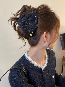 Detail of navy tweed bow hair claw with sparkling sequins worn on a low ponytail