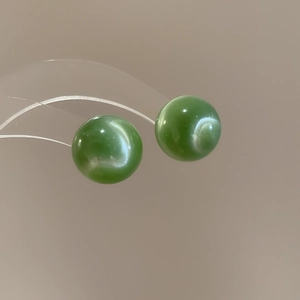 Macro shot of green cat-eye stone studs with smooth polished finish and light band