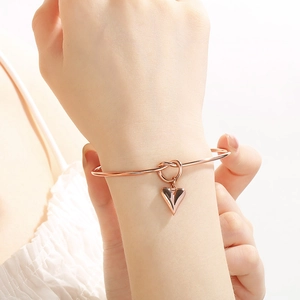 Minimalist knot bangle in rose gold finish with heart charm pendant for women