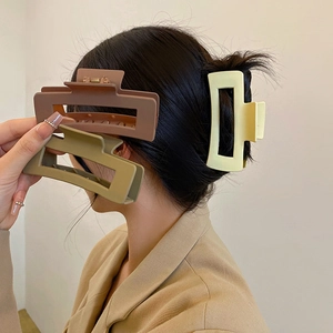 Large resin hair claw clip set in coffee and beige colors worn by a female model
