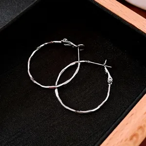 Minimalist silver hoop earrings with a textured hammered finish in a black jewelry box