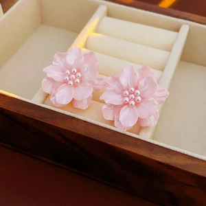 Détail de boucles d'oreilles fleurs roses en acrylique avec perles sur écrin