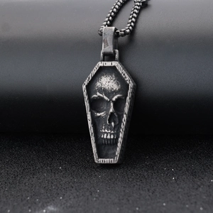 Close-up of vintage silver gothic coffin pendant with intricate skull relief details