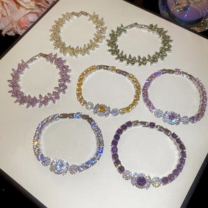 Collection of zircon flower tennis bracelets in seven colors on a white textured board