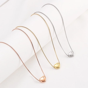 Three minimalist heart pendant necklaces in rose gold, gold, and silver stainless steel
